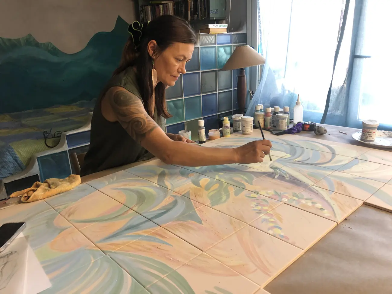 Inga Burina pintando azulejo cerámico en el estudio